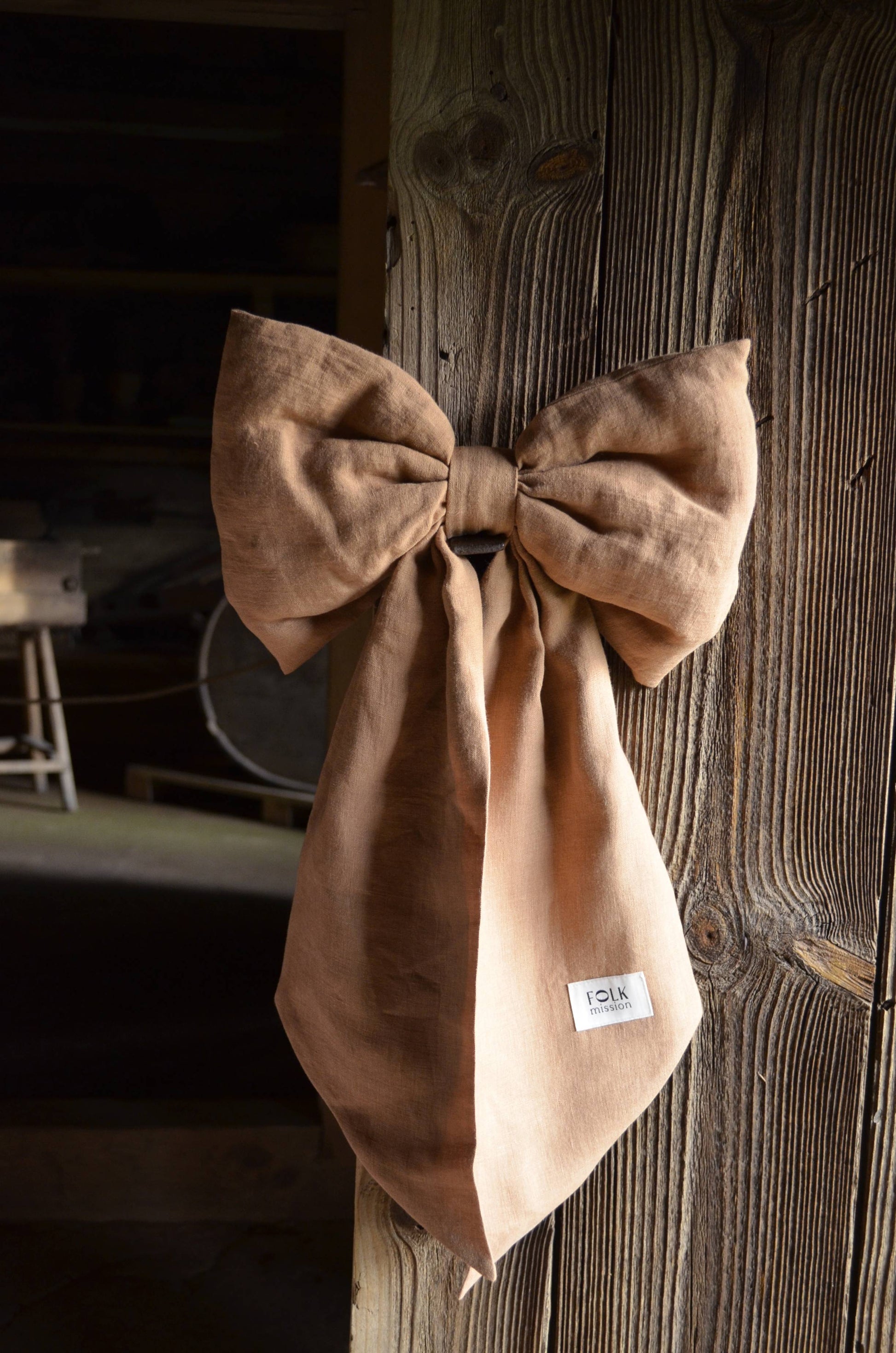 Brown bow tie with a label on a wooden surface